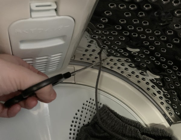 洗濯機の中の穴に紐が入ったをハサミで切る